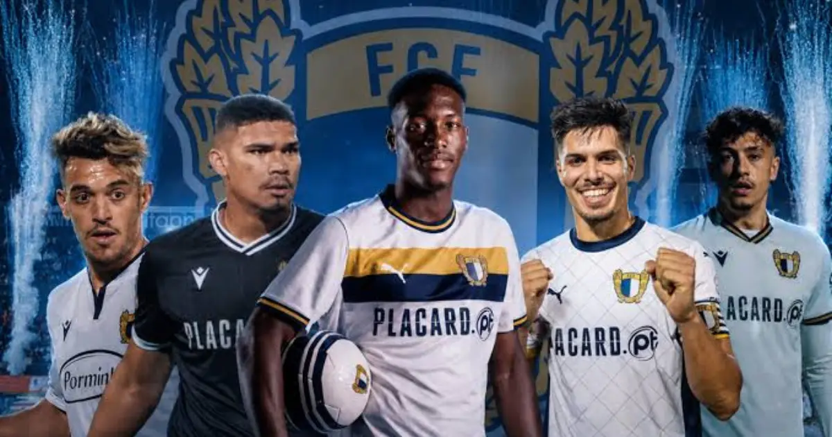 Jogadores em disputa de bola num relvado de futebol